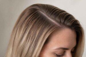 Zbliżenie blond włosów z wyraźnym przedziałkiem na środku głowy